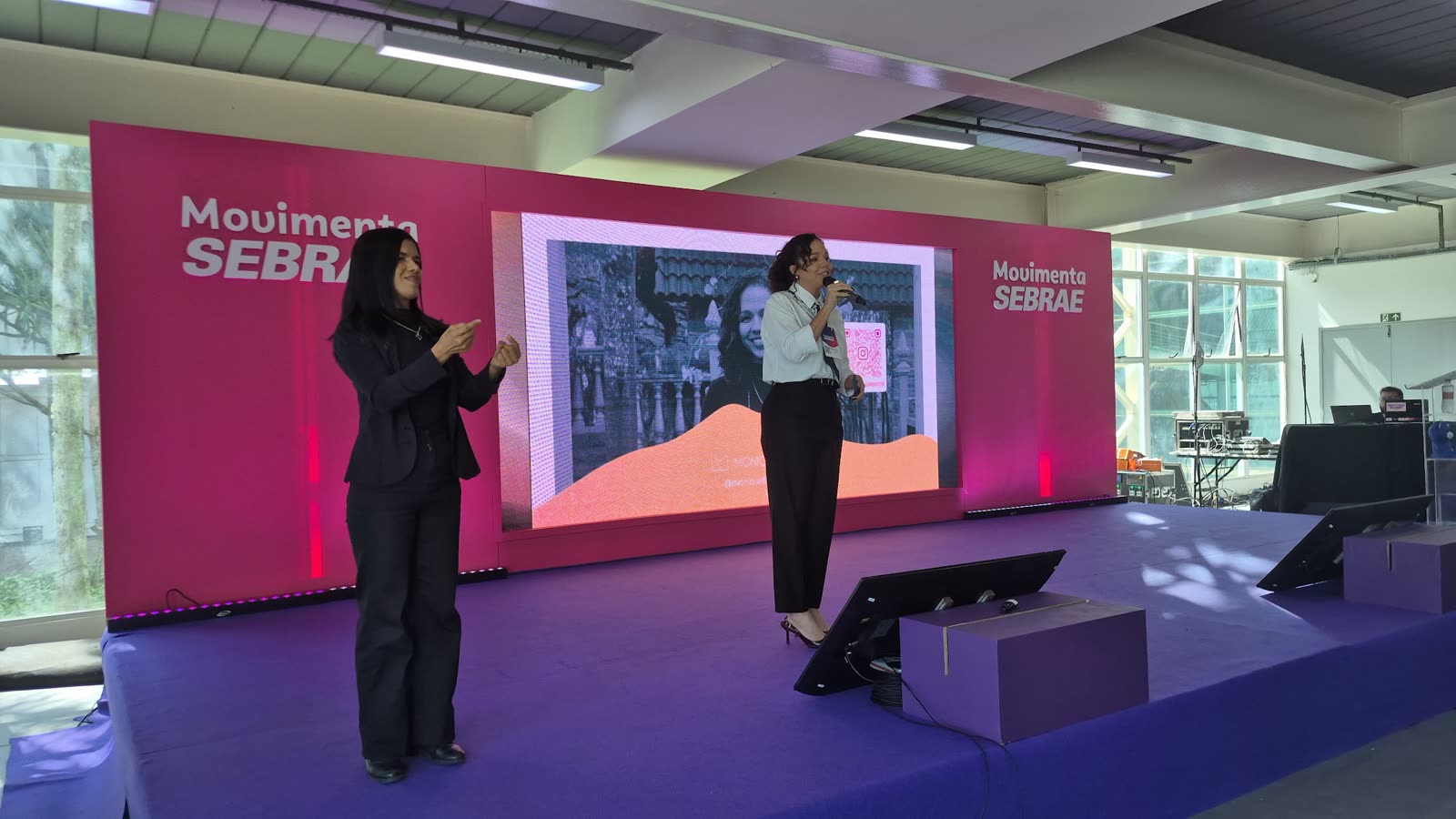 Monique Ferraz no palco do Movimenta Sebrae, com intérprete de Libras